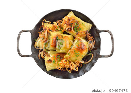 Fried Swabian meat ravioli (so called Maultaschen) with roasted onions, served in an iron frying pan 99467478