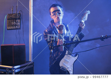 Cool artist blowing air kisses and acting flirty, playing guitar and having heavy metal style in studio. Sending kiss and being romantic or charming, singing alternative rock music with instrument. Cool artist blowing air kisses and acting flirty, playing guitar and having heavy metal style in studio. Sending kiss and being romantic or charming, singing alternative rock music with instrument. 99467777