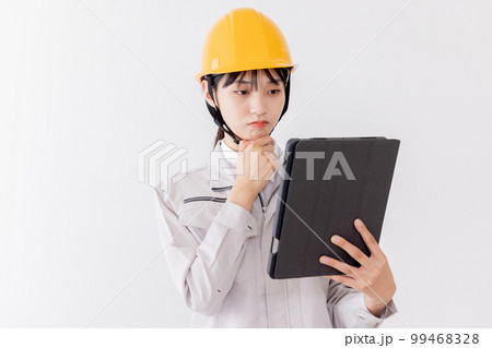 タブレットを使用しながら考える作業服の女性 タブレットを使用しながら考える作業服の女性 99468328
