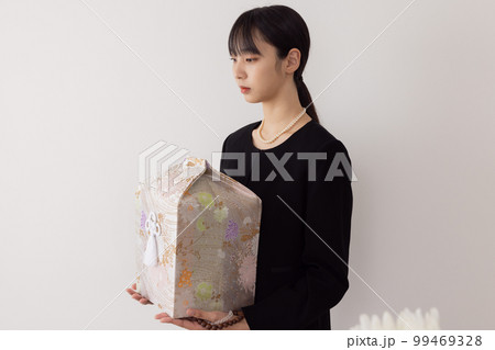 骨壺を持つ若い女性 99469328