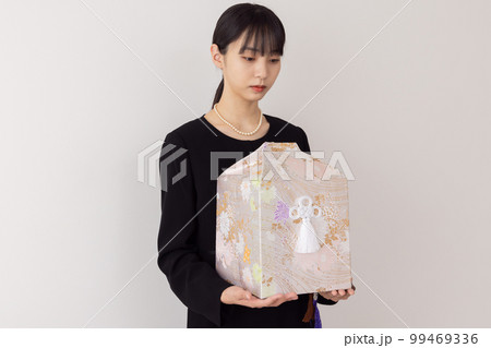 骨壺を持つ若い女性 99469336