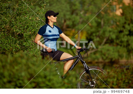 Happy young woman riding a bike in the park Happy young woman riding a bike in the park 99469748