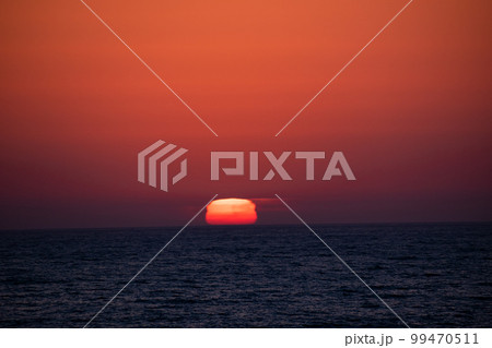 水平線に沈む達磨のような夕陽 99470511