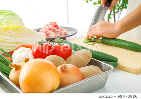 たくさんの野菜と料理をする女性 99470986
