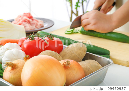 たくさんの野菜と料理をする女性 たくさんの野菜と料理をする女性 99470987