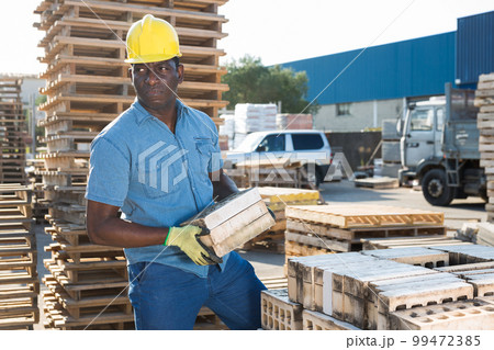 Worker stacking bricks in warehouse of building materials clpseup 99472385