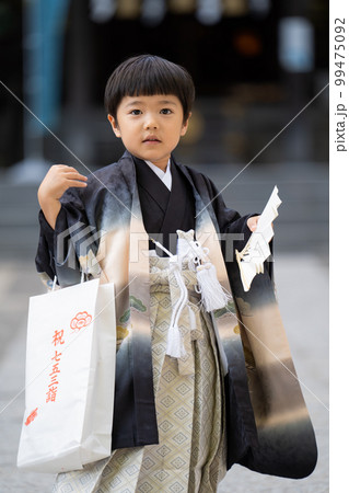 和服で七五三のお宮参りに来た5歳男児が神社の境内で扇子片手にポーズ