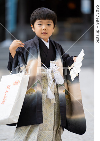和服で七五三のお宮参りに来た5歳男児が神社の境内で扇子片手にポーズを取る図(中央、寄り) 和服で七五三のお宮参りに来た5歳男児が神社の境内で扇子片手にポーズを取る図(中央、寄り) 99475095