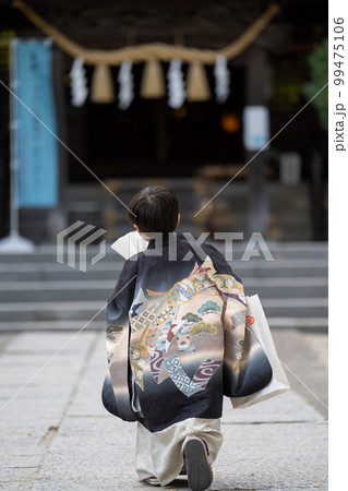 和服で七五三のお宮参りに来た5歳男児が神社の境内で扇子片手にポーズを取る図(引き、後ろ姿) 和服で七五三のお宮参りに来た5歳男児が神社の境内で扇子片手にポーズを取る図(引き、後ろ姿) 99475106