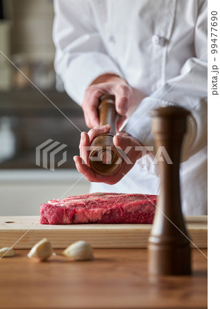 厚切りのステーキ肉にスパイスをふりかける料理人 99477690
