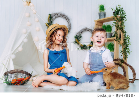 Happy laughing kids feeding rabbits learning to take care of an animal. Happy childhood Happy laughing kids feeding rabbits learning to take care of an animal. Happy childhood 99478187