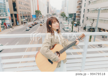街バックにギターを持った女性の写真 街バックにギターを持った女性の写真 99479518