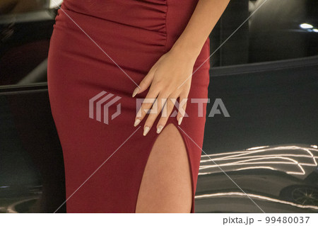 スリットの入ったセクシーな赤いドレスから覗く脚 99480037
