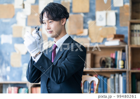 出張鑑定で貴金属をループで確認する男性スタッフ 99480261