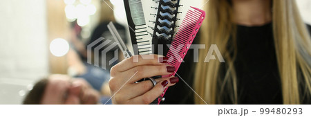 Hairdresser woman holding comb and scissors in barbershop 99480293