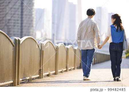 手を繋いで散歩する若いカップルの後ろ姿 手を繋いで散歩する若いカップルの後ろ姿 99482485