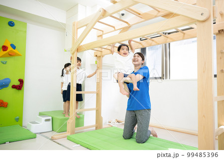 スポーツクラブや保育園でうんていをする子供　広角 99485396