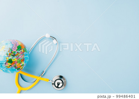 World Health Day. Top view yellow doctor stethoscope wrapped around world globe isolated on pastel blue background with copy space for text, Global healthcare, Health care and medical concept 99486401