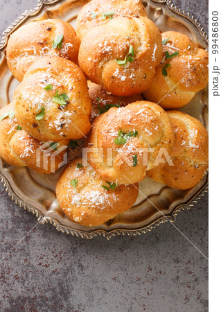 Garlic Herb and Cheese Rolls or Knots bread closeup on the plate on the table. Vertical top view Garlic Herb and Cheese Rolls or Knots bread closeup on the plate on the table. Vertical top view 99486800