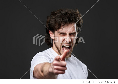 caucasian man pointing finger at you and the camera on dark gray background 99488373