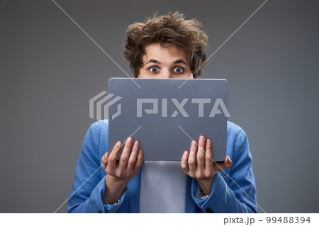 young man hiding his face with laptop young man hiding his face with laptop 99488394