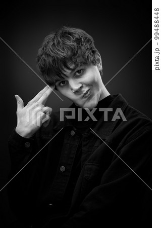 young man standing with finger gun pointed to head 99488448
