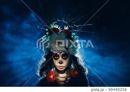 Woman with mexican skull halloween makeup on face. Day of the dead aka Dia de los Muertos and halloween party concept. Woman with mexican skull halloween makeup on face. Day of the dead aka Dia de los Muertos and halloween party concept. 99490256