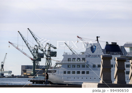 神戸港に停泊する客船と背後に見えるクレーンとメリケンパークの石像 99490650