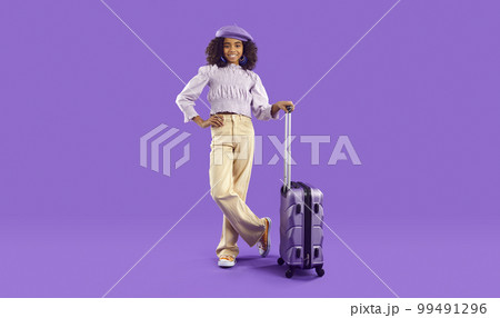 Happy African American child with holiday baggage standing on purple studio background Happy African American child with holiday baggage standing on purple studio background 99491296