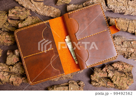 Open brown mens wallet with money and credit cards 99492562
