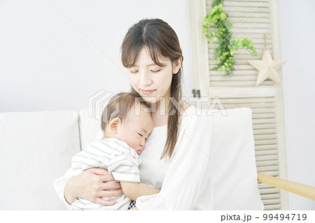 家で昼寝をする赤ちゃんを抱っこする母親 99494719