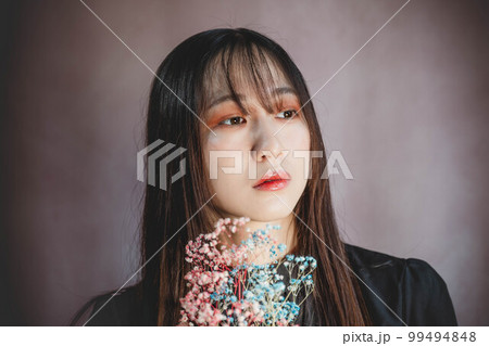 ピンク背景でカラフルな霞草を持った女性 99494848