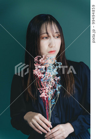 ドライフラワーをとグリーンバックと黒いワンピースの女性 99494859
