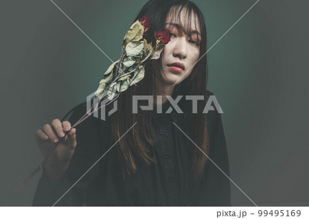 グリーンバックとバラを持った黒いワンピースの女性 99495169