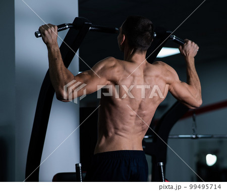 Back view of shirtless man with pull-ups in gym.  99495714