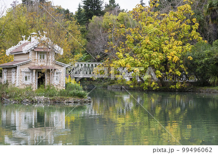 A bird house in the middle of a pond. This beautiful wooden fairy-tale house for swans. 10.10.2022 Russia, Adler, Southern Culture Park Autumn landscape 99496062