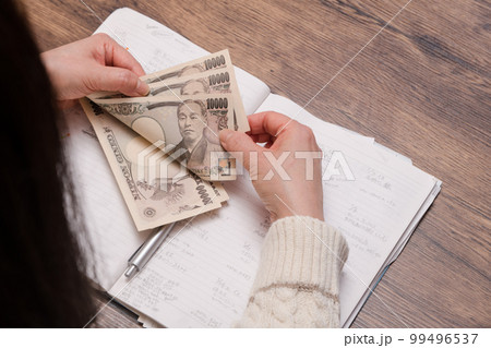 【家計簿をつける主婦が一万円札を数える】 99496537