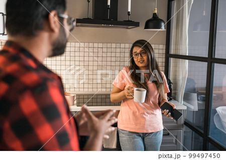 Indian woman talking to latino man in the kitchen. Lifestyle, healthy eating, multi ethnic concept. 99497450