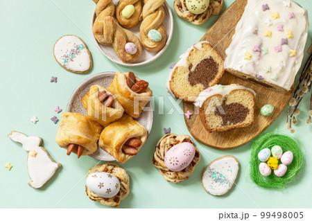 Festive dinner, Easter brunch. Happy Easter holiday food baking puff pastry and cupcake with Easter Bunny on pastel green background. View from above. 99498005