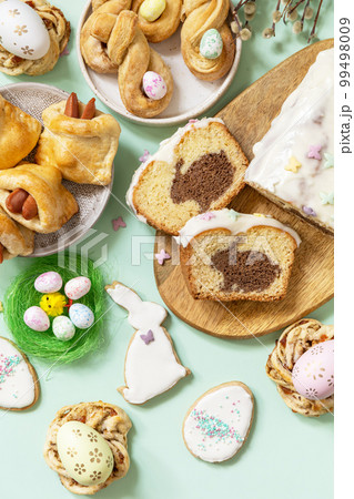 Festive dinner, Easter brunch. Happy Easter holiday food baking puff pastry and cupcake with Easter Bunny on pastel green background. View from above. 99498009
