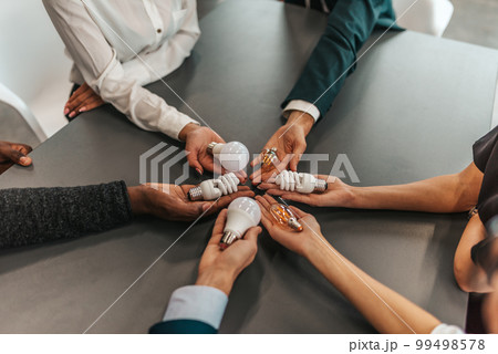 Teamwork and brainstorming concept with business people that share an idea with a lamp Teamwork and brainstorming concept with business people that share an idea with a lamp 99498578