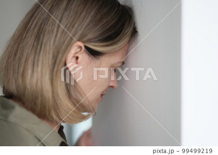 Sad woman, leans against the wall, closeup Sad woman, leans against the wall, closeup 99499219