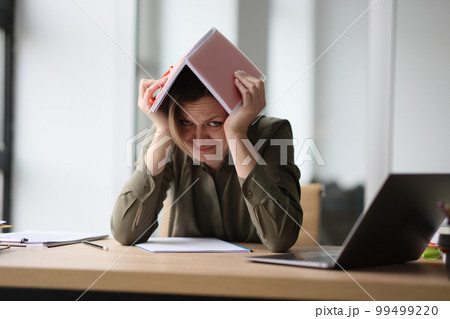 The woman in the office hid under a notebook on her head The woman in the office hid under a notebook on her head 99499220