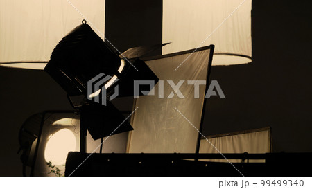 Film light for video production camera in studio set. Use as studio photo shoot light. Big LED spot light 5000w and diffuser or black panel create light like sun light can make daytime or golden hour Film light for video production camera in studio set. Use as studio photo shoot light. Big LED spot light 5000w and diffuser or black panel create light like sun light can make daytime or golden hour 99499340