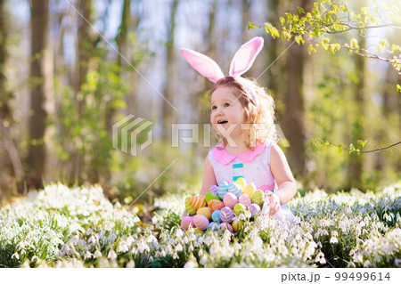 Child with bunny ears on garden Easter egg hunt Child with bunny ears on garden Easter egg hunt 99499614