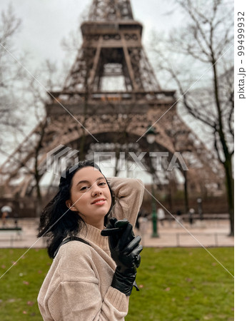Lady near Eiffe Tower in Paris, France was made in winter. No snow, only some rain on the street. Lady near Eiffe Tower in Paris, France was made in winter. No snow, only some rain on the street. 99499932