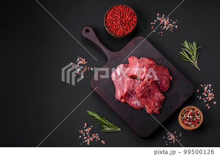 Raw beef cut into several pieces on a wooden cutting board 99500126