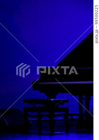 開演前の薄暗いライブハウスのステージに置かれたグランドピアノ 99500225