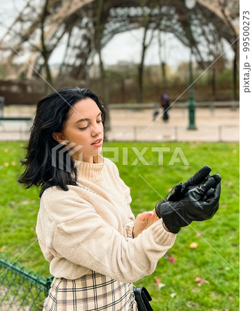 Lady near Eiffe Tower in Paris, France was made in winter. No snow, only some rain on the street. Lady near Eiffe Tower in Paris, France was made in winter. No snow, only some rain on the street. 99500273