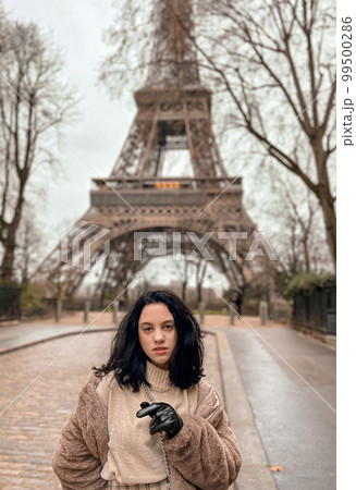 Lady near Eiffe Tower in Paris, France was made in winter. No snow, only some rain on the street. Lady near Eiffe Tower in Paris, France was made in winter. No snow, only some rain on the street. 99500286